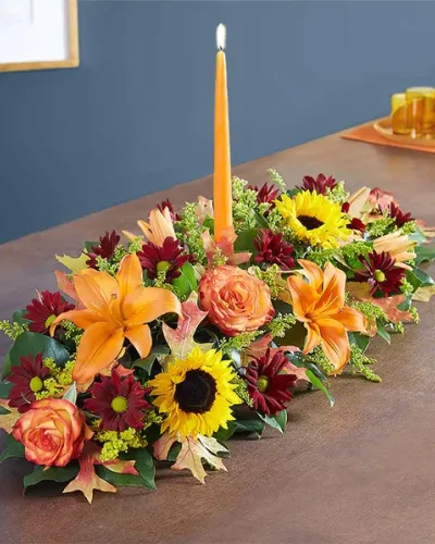 The rich beauty of the European countryside comes alive in our best-selling fall centerpiece. Crafted by our artisan florists, it&rsquo;s filled with a gathering of fresh-picked blooms in brilliant colors and finished with an orange candle to warm hearts and homes.