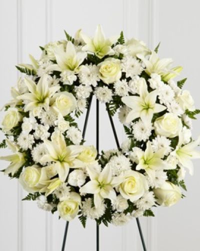 The FTD&reg; Treasured Tribute&trade; Wreath offers peaceful wishes of heartfelt sympathy with each delicate bloom. Bright white roses, Asiatic lilies, mini carnations and cushion poms are beautifully arranged to form an elegant accented with lush and vibrant greens. Displayed on a wire easel, this gorgeous tribute is a wonderful symbol of eternal life and sweet serenity.