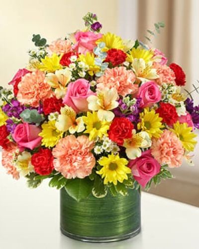 <p>Express your condolences with a sympathy arrangement designed by our florists to offer comfort to friends and family during difficult times of loss. The graceful, bright-toned arrangement of roses, stock, alstroemeria, carnations, daisy poms, mini carnations and monte casino is gathered with variegated pittosporum and spiral eucalyptus in a stylish clear glass cylinder vase wrapped with a Ti leaf ribbon.</p>