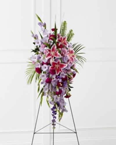 The FTD&reg; Tender Touch&trade; Standing Spray creates an elegant display of beauty and color to enhance their final tribute. Lavender gladiolus, Stargazer lilies, fuchsia carnations, purple larkspur, lavender Peruvian lilies, lavender chrysanthemums, sword fern fronds, emerald palm fronds and other assorted greens are gorgeously arranged to create a sophisticated standing spray. Displayed on a wire easel, this arrangement will add to the sophistication of their service with each fragrant bloom.