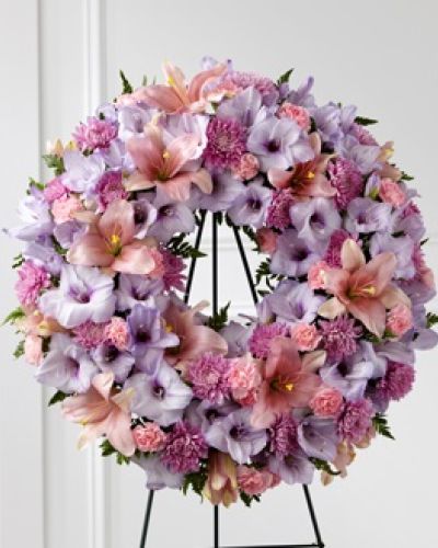 Our Beloved Friend&trade; Wreath beautifully honors a life that was cherished by so many. This classic arrangement stands tall with an array of lilies, gladiolus and carnations in lavender and pink shades to express your love for the friends who truly feel like family.