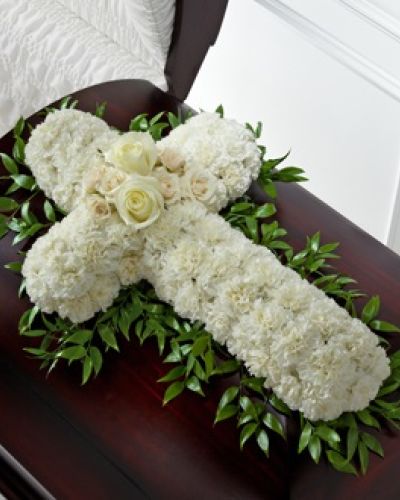 The FTD&reg; Peaceful Memories&trade; Casket Spray is a gorgeous way to commemorate the faith and devotion of the deceased. White carnations are arranged in the shape of a cross accented in the middle with white roses and spray roses and along the sides with lush greens to create a lovely casket spray that brings peace and solace to those that attend their final farewell.