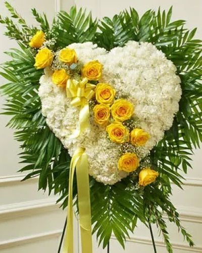 <p>This solid heart standing spray, accented with a slash of beautiful yellow roses, is a loving symbol of your sympathy and support. White carnations, yellow roses, baby's breath and more make up this solid heart with oasis in mache, tied to the wire easel with satin ribbon. Traditionally sent directly to the funeral home by family members or friends and displayed on a stand.</p>