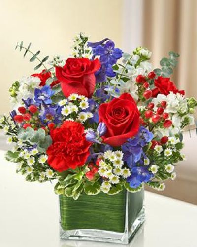 This lovely red, white and blue arrangement offers a beautiful reflection of your patriotism.
Fresh red roses, delphinium, stock, carnations and hypericum, designed in a cube vase make any occasion special.