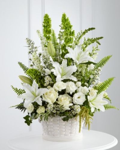 The FTD® In Our Thoughts™ Arrangement is a symbol of pure peace and caring kindness. White roses, tulips, freesia, Oriental lilies, double lisianthus, monte casino asters, and snapdragons, are beautifully offset by bright green Bells of Ireland, ivy vines, and an assortment of lush greens to create an elegant display that conveys your deepest sympathies for their loss. Arrives in a large round whitewash basket.