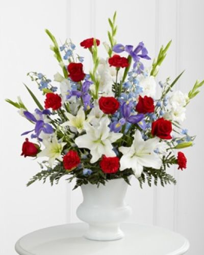 <p>A dramatic floral salute respectfully features a heroic color palette of red, white and blue to honor the life of a hero. Our Gratitude™ Arrangement is designed with lilies, irises, delphinium and roses to share your sympathies with reverence and respect. While the lilies may initially arrive in bud form, they beautifully transform as they open.</p>