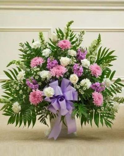 This delicate floor basket arrangement helps you convey your care and concern with beautiful lavender flowers to represent a vibrant life and fresh white blooms to symbolize purity and peace. This arrangement features fresh white roses, snapdragons, carnations, lavender mums, lavender stock and more. Appropriate for family, friends or business associates to send directly to the funeral home.